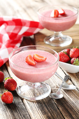 Tasty strawberry mousse in glass on brown wooden table