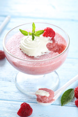 Sweet raspberry mousse in glass on blue wooden table