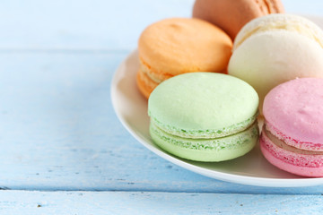 French colorful and tasty macarons in plate on wooden table