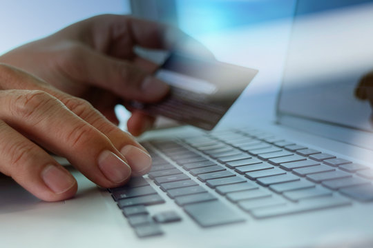 close up of hands using laptop and holding credit card as Online