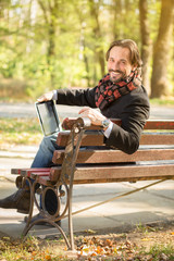 Obraz premium Middle-aged man resting on the bench outdoors