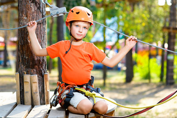 Happy boy having fun when playing at adventure park, holding