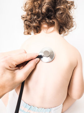 Child at pediatrician with health check using stethoscope on bac