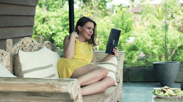 Young, pretty woman chatting on tablet computer on terrace
