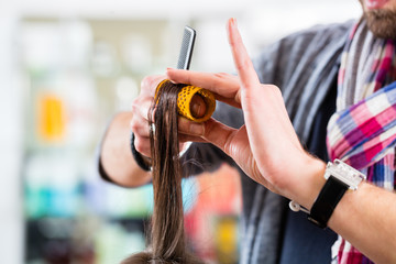 Hairdresser styling woman hair in shop