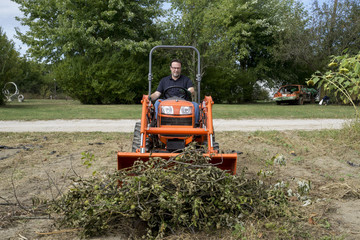 Tree Trimmer Pushing Pile Of Tree Limbs