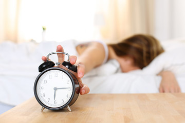Sleepy young woman trying kill alarm clock - obrazy, fototapety, plakaty