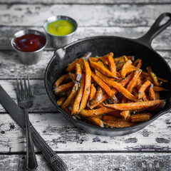 Sweet potato fries in cast iron skillet on wooden background