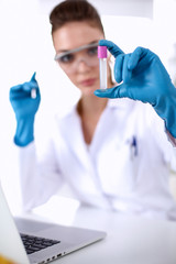 Woman researcher is surrounded by medical vials and flasks