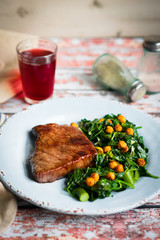 Fresh steak with green salad on rustic wooden background