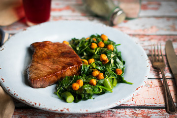 Fresh steak with green salad on rustic wooden background