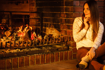 Woman relaxing at fireplace. Winter home.
