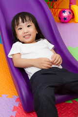 Obraz premium Asian Chinese little girl playing on the slide