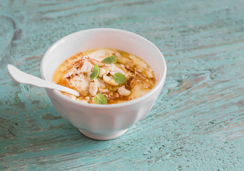 Greek yogurt with honey and nuts in a white bowl on blue wooden surface, vintage and rustic style
