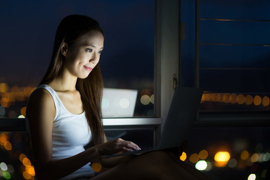 Woman using the laptop computer and sitting beside the window