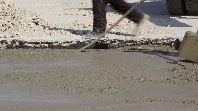 Construction workers compacting liquid cement into a runway construction