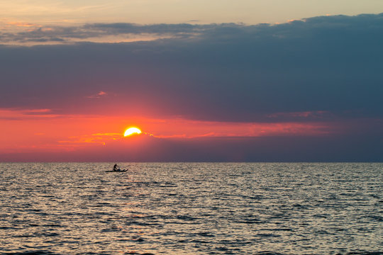 Man rowing at sunset on a traditional italian boat "pattino"