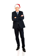 Full length businessman wearing santa hat.