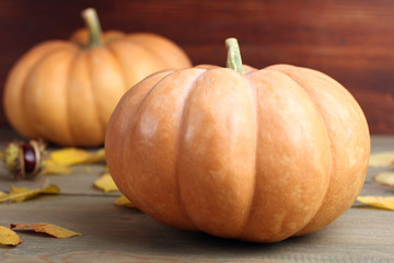 pumpkin with leaves and chestnuts on wooden background