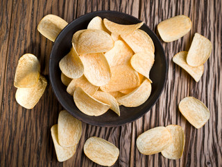 Potato chips on a wooden background.