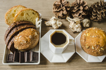 Black coffee in a white cup and saucer with pastries with chocolate on a wooden board