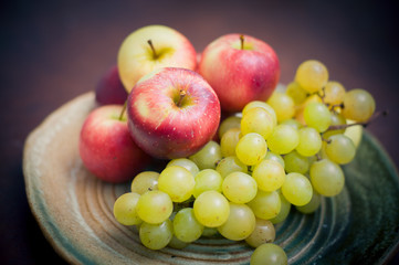 Plate with fresh autumnal fruits, apples and grapes
