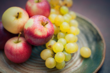 Plate with fresh autumnal fruits. apples in selective focus