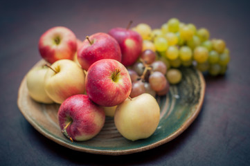 Plate with fresh autumnal fruits. apples in selective focus
