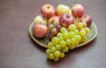Plate with fresh autumnal fruits. grapes in selective focus