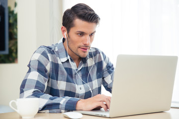Man using laptop with headphones at home