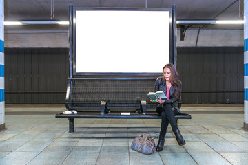 Railway station billboard and reading woman