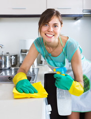 Adult girl dusting surfaces in kitchen