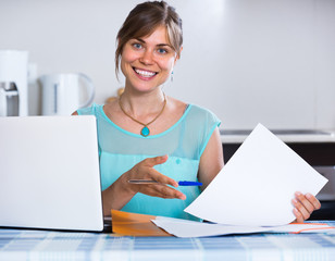 Smiling woman with documents at kitchen.