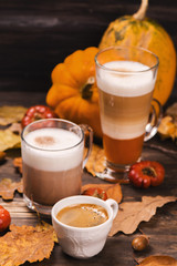 Autumn hot coffee drinks. Pumpkin latte, hot chocolate and espresso on wooden rustic background. Selective focus