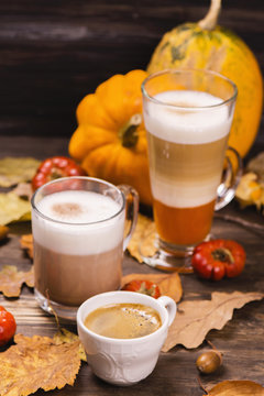 Autumn hot coffee drinks. Pumpkin latte, hot chocolate and espresso on wooden rustic background. Selective focus