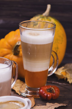 Hot pumpkin latte on wooden background. Selective focus