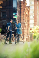Obraz premium Young couple sitting on a bicycle opposite the city 