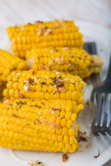 Roasted sweet corn on the cob on white plate
