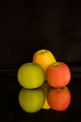 Green, Golden and Pink Lady Apple isolated on black with mirror reflection