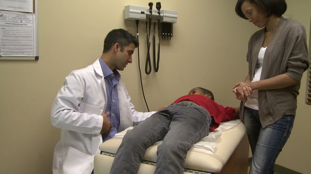 Doctor checks young boy's abdomen