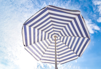 Blue and white sun beach umbrella and blue sky with clouds