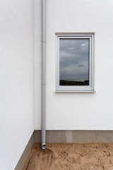 New rain gutter on a white wall with window