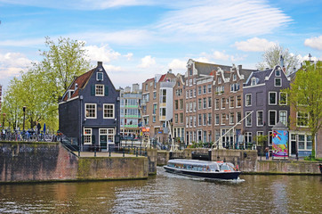 Fototapeta premium Beautiful cityscape with buildings and boat on the canal in Amst