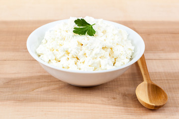 Fresh cottage cheese in a white bowl with spoon.