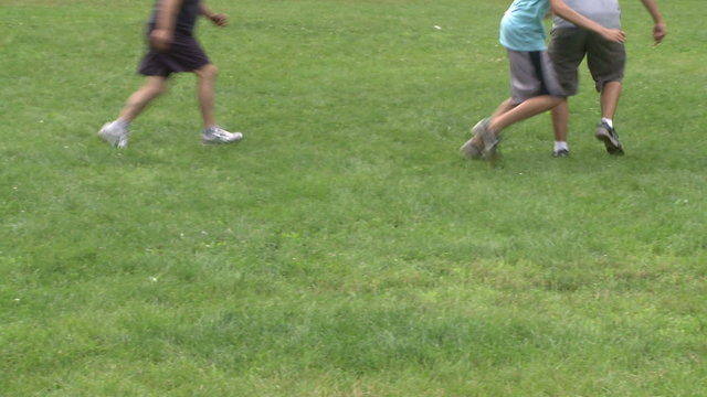 Boys playing soccer in a park at a picnic