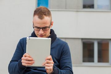 Stylish guy connected on internet with tablet in town. Negative emotions.