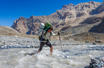 Hiker crossing mountain river