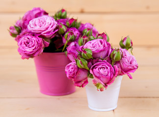 Pink roses in a vase on wooden background