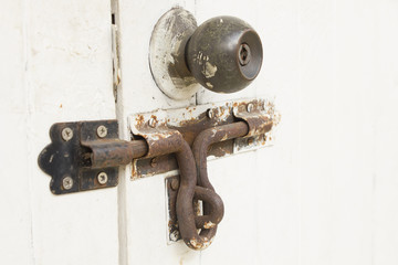 Rusty bolt and doorknob on white wooden door