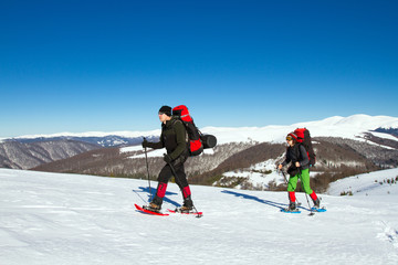 Winter hiking in the mountains on snowshoes with a backpack and tent.